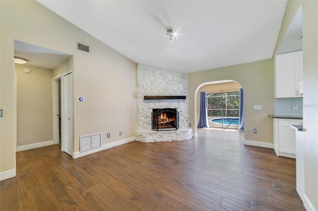 unfurnished living room with visible vents, wood finished floors, baseboards, and vaulted ceiling