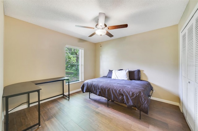 bedroom featuring baseboards, wood finished floors, a closet, and a textured ceiling