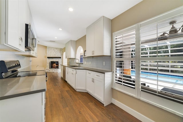 668 Coral Way, Winter Springs, FL 32708 - kitchen with backsplash, dark countertops, dark wood finished floors, stainless steel appliances, and a sink