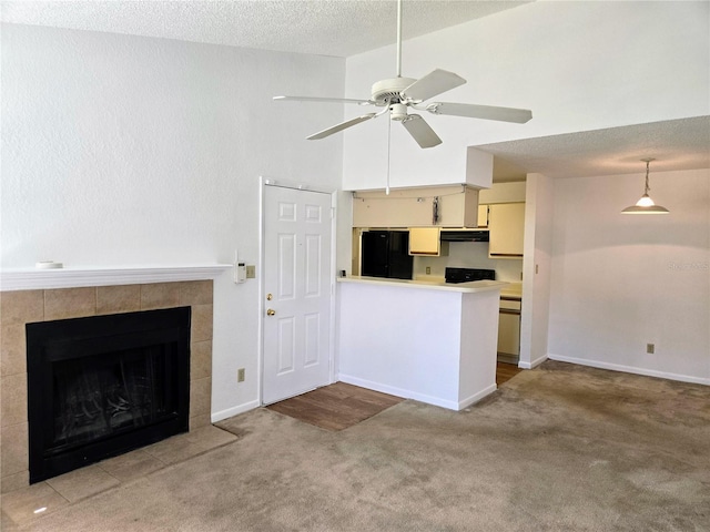 interior space featuring a textured ceiling, ceiling fan, a tiled fireplace, and carpet floors