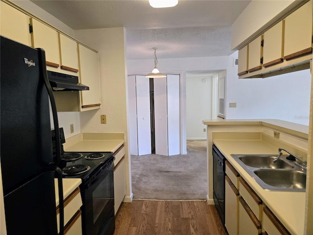 kitchen with cream cabinetry, black appliances, dark hardwood / wood-style floors, and sink