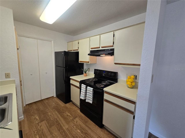 4401 Thornbriar Ln Unit 202, Orlando, FL 32822 - kitchen featuring black appliances, under cabinet range hood, wood finished floors, light countertops, and a sink