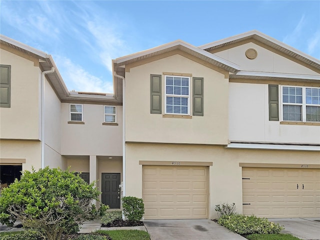 townhome / multi-family property with concrete driveway, an attached garage, and stucco siding