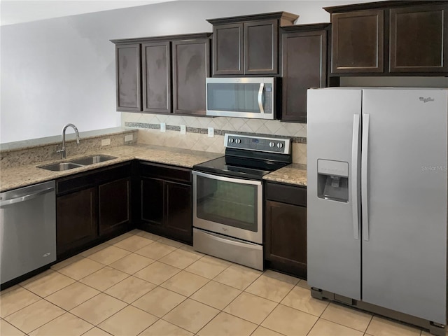 kitchen featuring a sink, light stone counters, stainless steel appliances, light tile patterned floors, and decorative backsplash