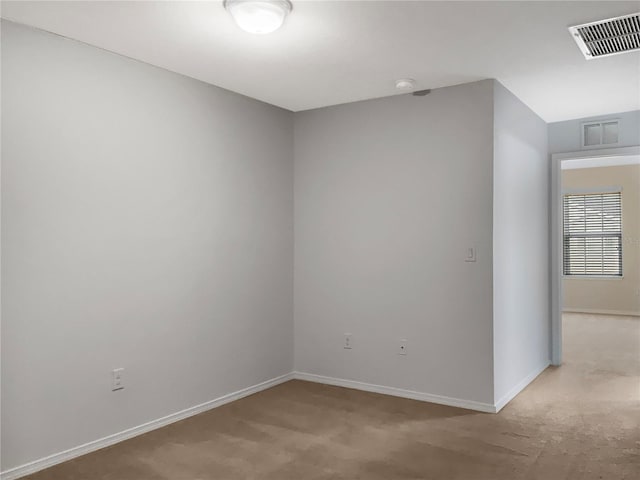 empty room with light colored carpet, baseboards, and visible vents