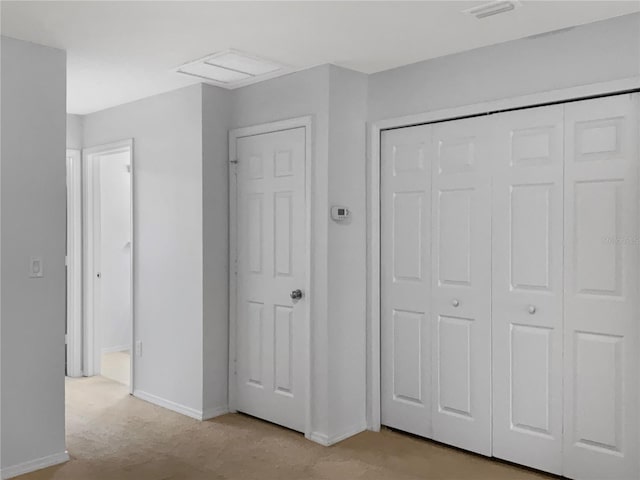 unfurnished bedroom featuring attic access, baseboards, a closet, and visible vents