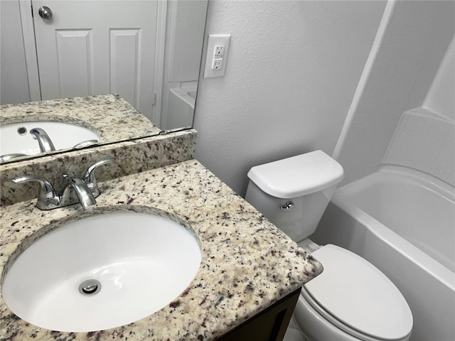 full bathroom with toilet, shower / washtub combination, vanity, and a textured wall