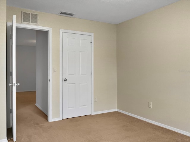 unfurnished bedroom featuring baseboards, visible vents, and light carpet