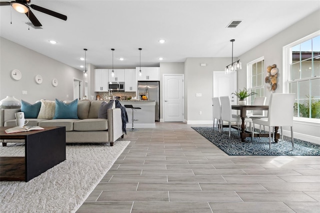 living room with light hardwood / wood-style flooring, ceiling fan, and a healthy amount of sunlight