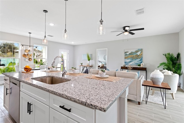 kitchen with decorative light fixtures, sink, ceiling fan, stainless steel dishwasher, and white cabinets