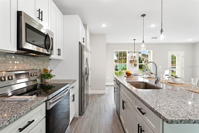 kitchen with appliances with stainless steel finishes, a center island with sink, white cabinetry, and sink