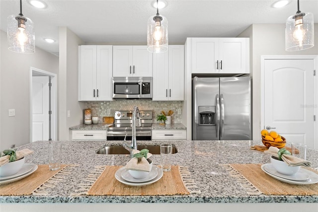 kitchen featuring hanging light fixtures, stainless steel appliances, decorative backsplash, and white cabinets