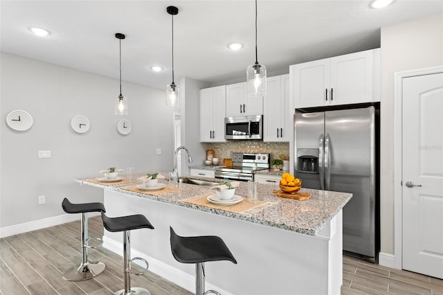 kitchen featuring light hardwood / wood-style flooring, appliances with stainless steel finishes, an island with sink, and sink