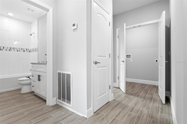 full bathroom featuring vanity, toilet, hardwood / wood-style flooring, and tiled shower / bath