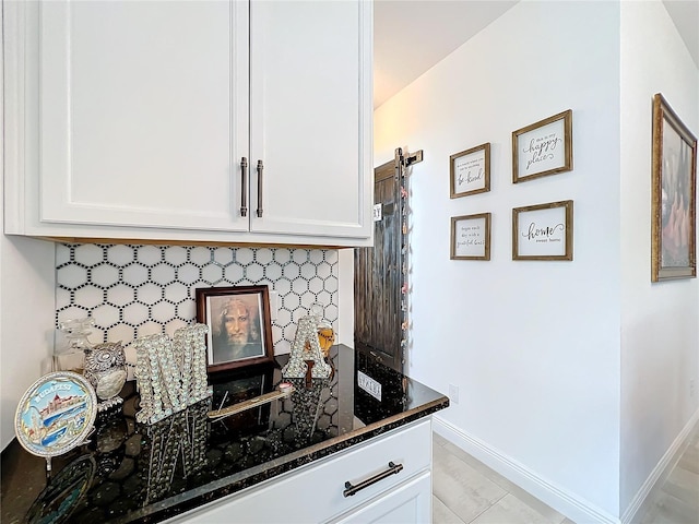 bar featuring white cabinets, dark stone countertops, tasteful backsplash, and light tile patterned flooring