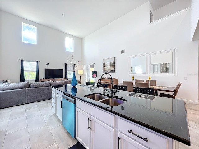 kitchen featuring a center island with sink, dishwasher, sink, a high ceiling, and white cabinets