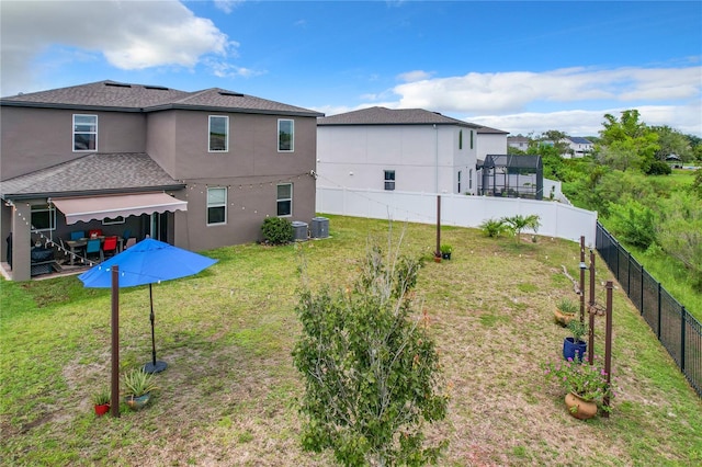 back of property with a yard and central AC