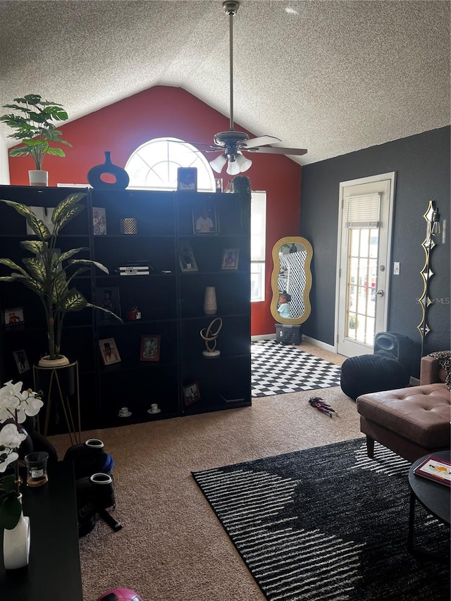 living room featuring lofted ceiling, ceiling fan, carpet floors, and a textured ceiling