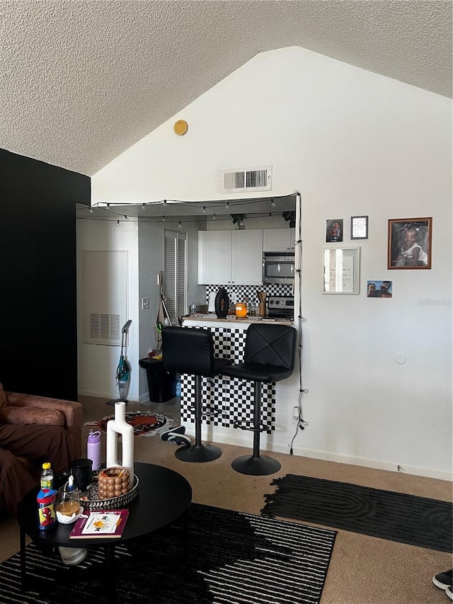 interior space featuring lofted ceiling, appliances with stainless steel finishes, and a textured ceiling