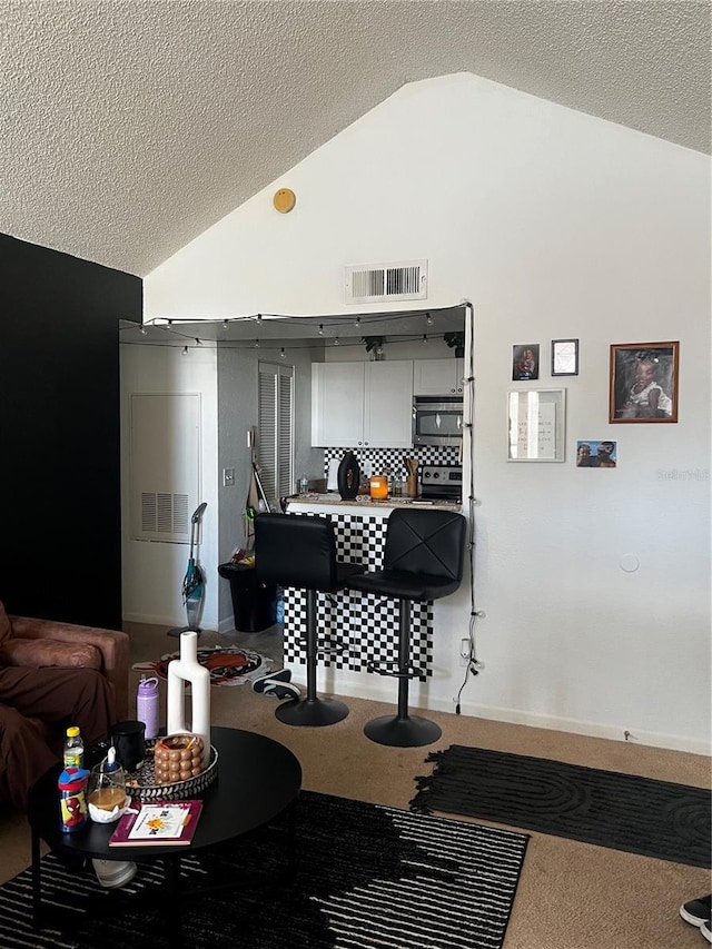 interior space with lofted ceiling, a textured ceiling, and visible vents