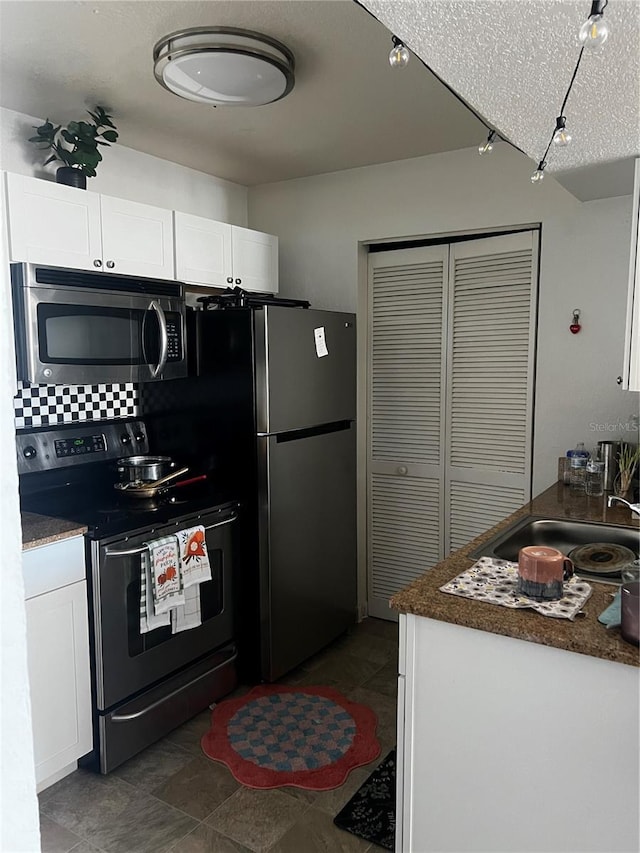 kitchen featuring appliances with stainless steel finishes, dark countertops, and white cabinetry