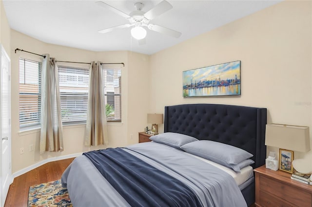 bedroom featuring ceiling fan, hardwood / wood-style floors, and multiple windows