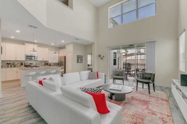 living room with plenty of natural light, a high ceiling, and light hardwood / wood-style floors