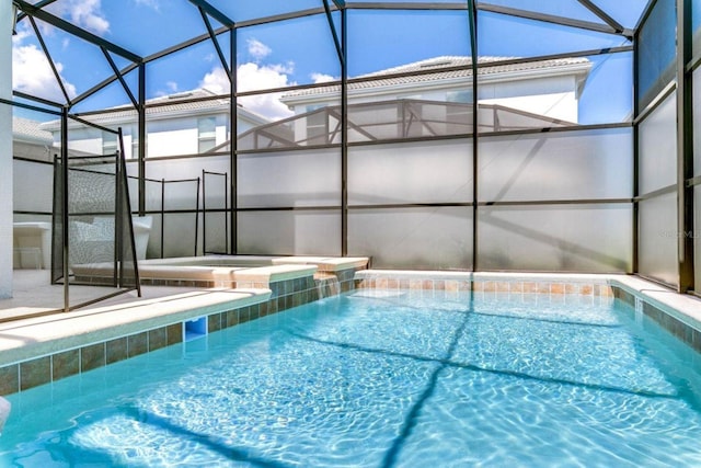 view of pool with glass enclosure and an in ground hot tub