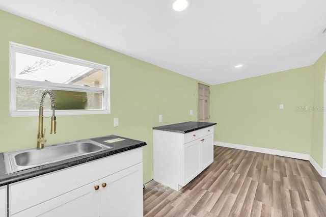 kitchen featuring light wood-type flooring, sink, and white cabinetry