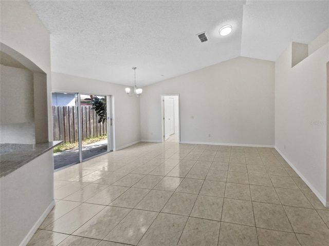 spare room featuring lofted ceiling, light tile patterned floors, a notable chandelier, and a textured ceiling