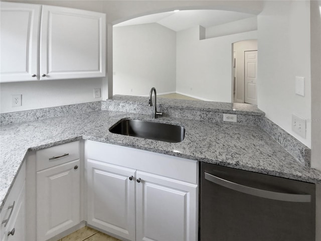 kitchen with light tile patterned floors, dishwasher, light stone countertops, white cabinetry, and sink