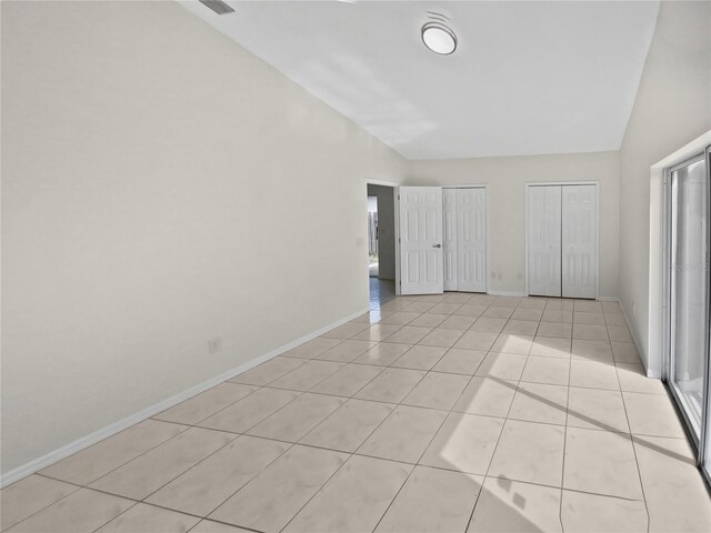 spare room with light tile patterned flooring and vaulted ceiling