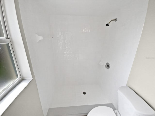 bathroom featuring tiled shower and toilet