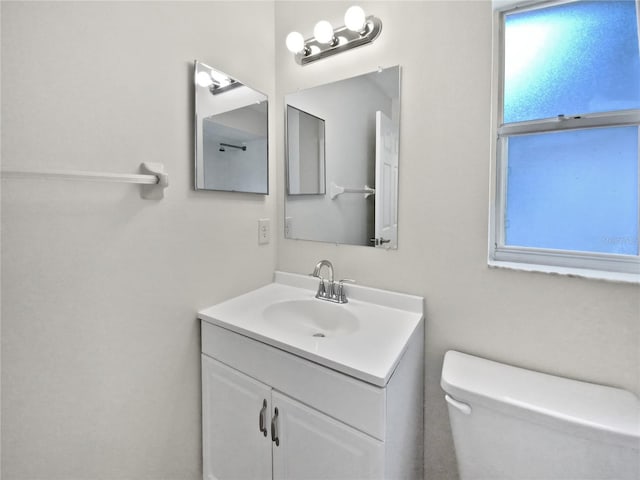 bathroom with toilet, a wealth of natural light, and vanity