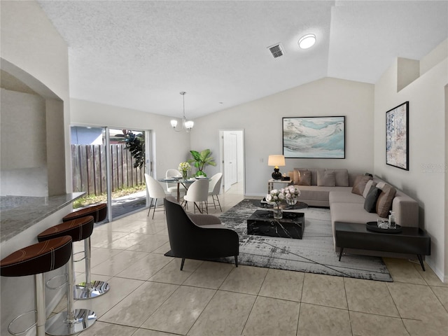 living room with an inviting chandelier, vaulted ceiling, a textured ceiling, and light tile patterned floors