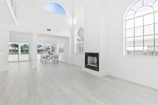 unfurnished living room with light wood-type flooring, a multi sided fireplace, and a wealth of natural light