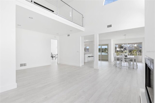 unfurnished living room featuring a towering ceiling and light hardwood / wood-style floors