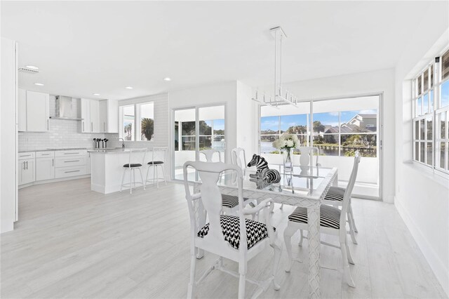 dining area with a healthy amount of sunlight, an inviting chandelier, and light hardwood / wood-style flooring