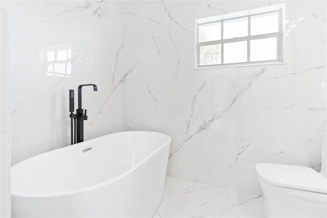 bathroom featuring a washtub and toilet