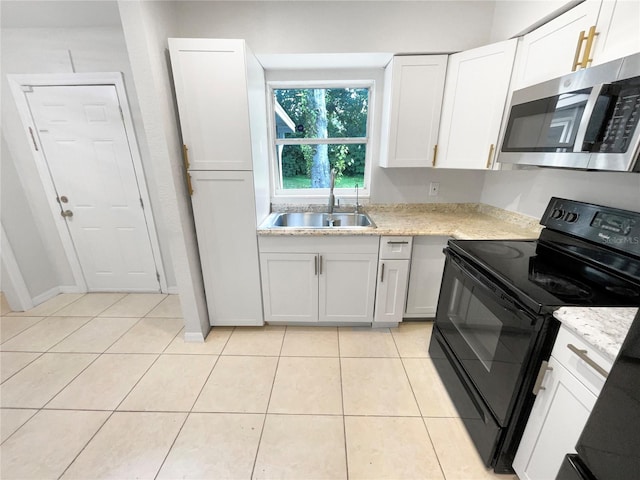 kitchen with light tile patterned floors, white cabinetry, light stone counters, and black range with electric stovetop