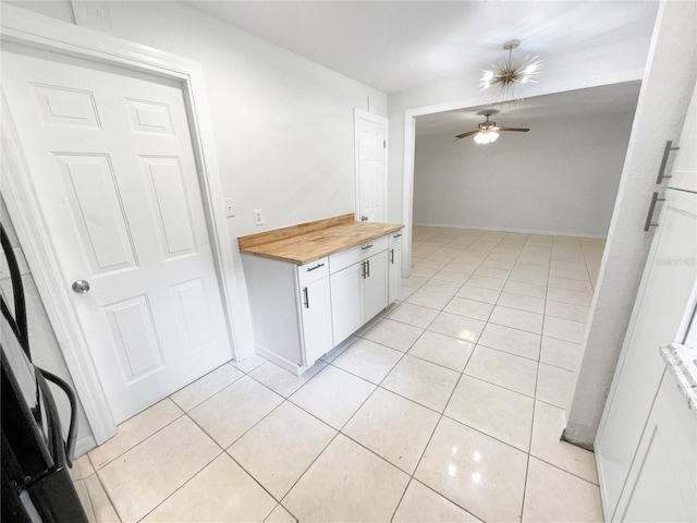 interior space with white cabinets, butcher block counters, light tile patterned floors, and ceiling fan