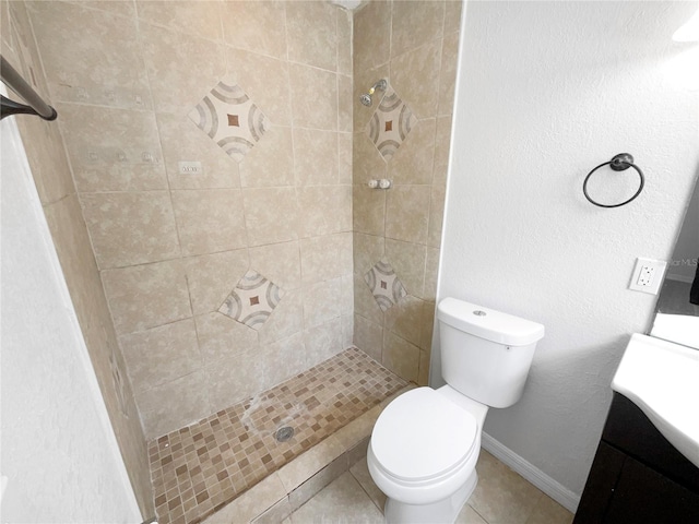 bathroom with tile patterned floors, toilet, a tile shower, and vanity