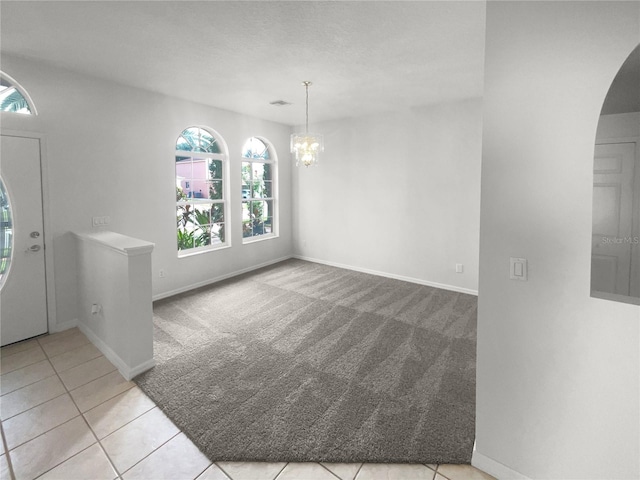 carpeted foyer with a chandelier