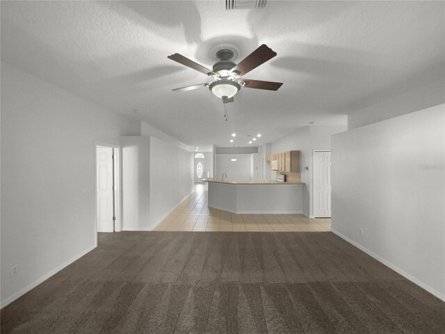 unfurnished living room with a textured ceiling, light colored carpet, and ceiling fan