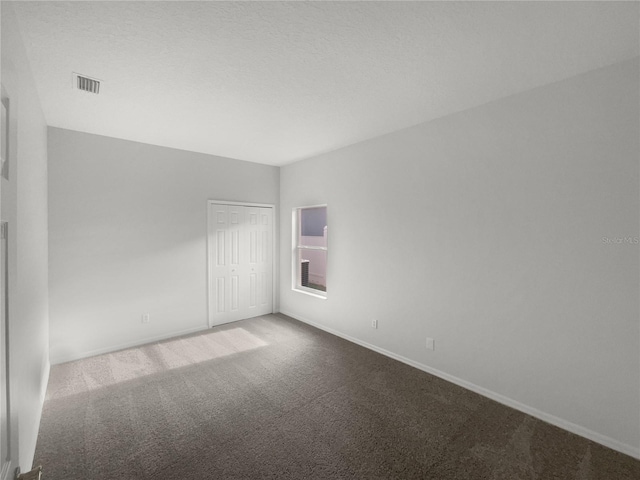 carpeted empty room featuring a textured ceiling