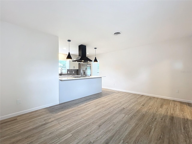 kitchen featuring stainless steel fridge, pendant lighting, light hardwood / wood-style flooring, island range hood, and white cabinetry