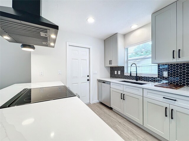 kitchen featuring light hardwood / wood-style flooring, backsplash, exhaust hood, sink, and stainless steel dishwasher