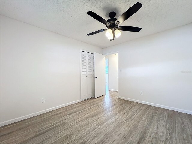 unfurnished bedroom featuring a closet, ceiling fan, a textured ceiling, and light hardwood / wood-style flooring