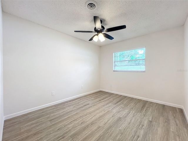 spare room featuring light wood-type flooring, a textured ceiling, and ceiling fan