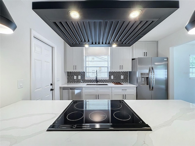 kitchen with white cabinets, backsplash, stainless steel appliances, sink, and exhaust hood